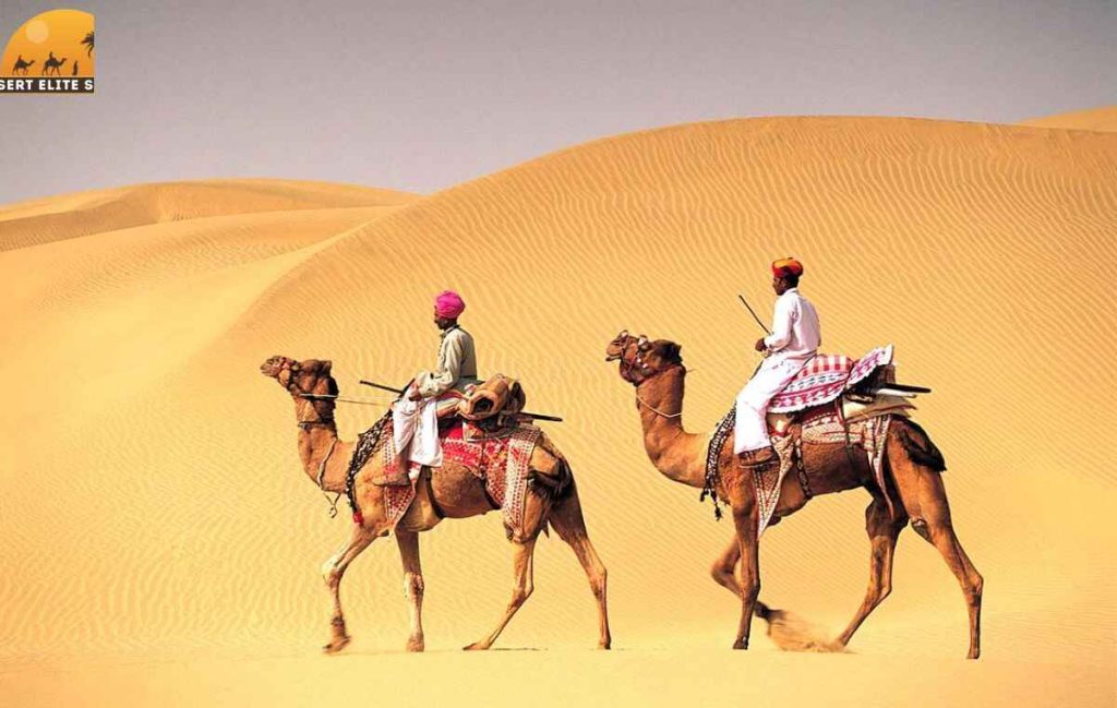 Tourists enjoying camel safari Dubai across sand dunes