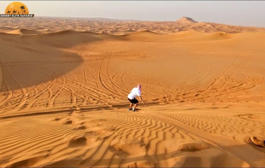Tourist sandboarding on golden desert dunes in Dubai desert safari – adventure activity 2025